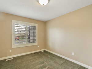 Unfurnished room with baseboards and dark carpet