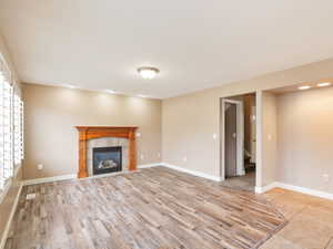 Unfurnished living room with light wood finished floors and a tiled fireplace