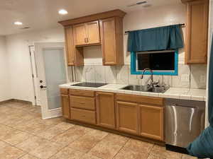 Kitchen with tile countertops, dishwasher, decorative backsplash, wood finish cabinetry, and recessed lighting