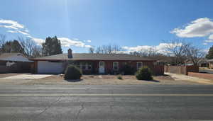 Ranch-style home with an attached garage, concrete driveway, and a chimney