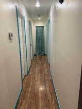 Corridor featuring a textured wall and dark wood-style flooring