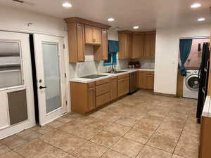 Kitchen featuring tile counters, recessed lighting, black appliances, washer / dryer, and tasteful backsplash