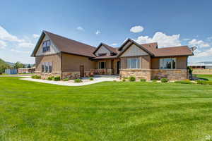View of front of property with stone siding, a porch, a front lawn, a shingled roof, and board and batten siding