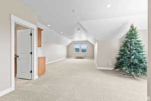 Additional living space with vaulted ceiling, light colored carpet, and recessed lighting