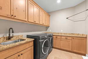 Laundry area featuring separate washer and dryer, cabinet space, and light tile patterned floors