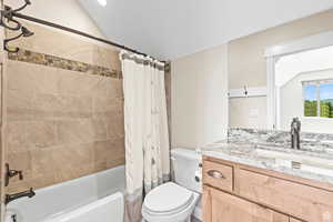 Full bathroom featuring vanity, shower / tub combo with curtain, and lofted ceiling