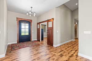 Entryway featuring a barn door, light wood-type flooring, and hanging lights