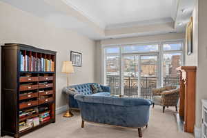 Sitting room with a tray ceiling, ornamental molding, and light colored carpet