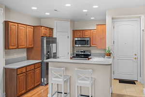 Kitchen featuring light countertops, stainless steel appliances, a breakfast bar, a peninsula, and recessed lighting