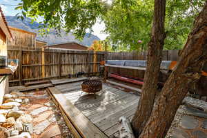 Wooden deck featuring an outdoor fire pit, a mountain view, and a fenced backyard