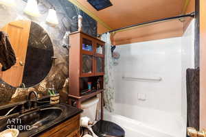 Full bath featuring vanity, shower / bath combo with shower curtain, and ornamental molding