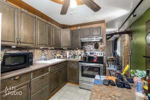 Kitchen with a ceiling fan, stainless steel electric range, black microwave, light countertops, and light floors