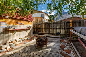 Wooden deck featuring a fenced backyard, a fire pit, and a mountain view