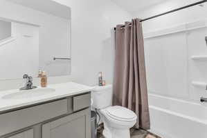 Full bath featuring shower / bath combo, vanity, and light wood-style floors