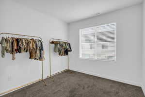 Unfurnished bedroom with baseboards and dark carpet