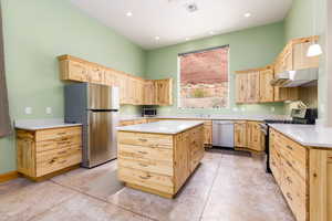Kitchen featuring light wood finish cabinetry, stainless steel appliances, a kitchen island, and recessed lighting