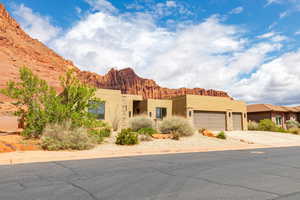 Pueblo-style house featuring stucco siding, a garage, a mountain view, and concrete driveway