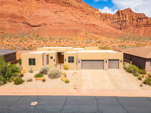 View of front of property with stucco siding, concrete driveway, an attached garage, a desert view, and a mountain view