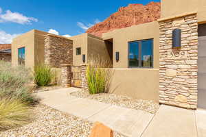 Entrance to property with stone siding, stucco siding, and a gate