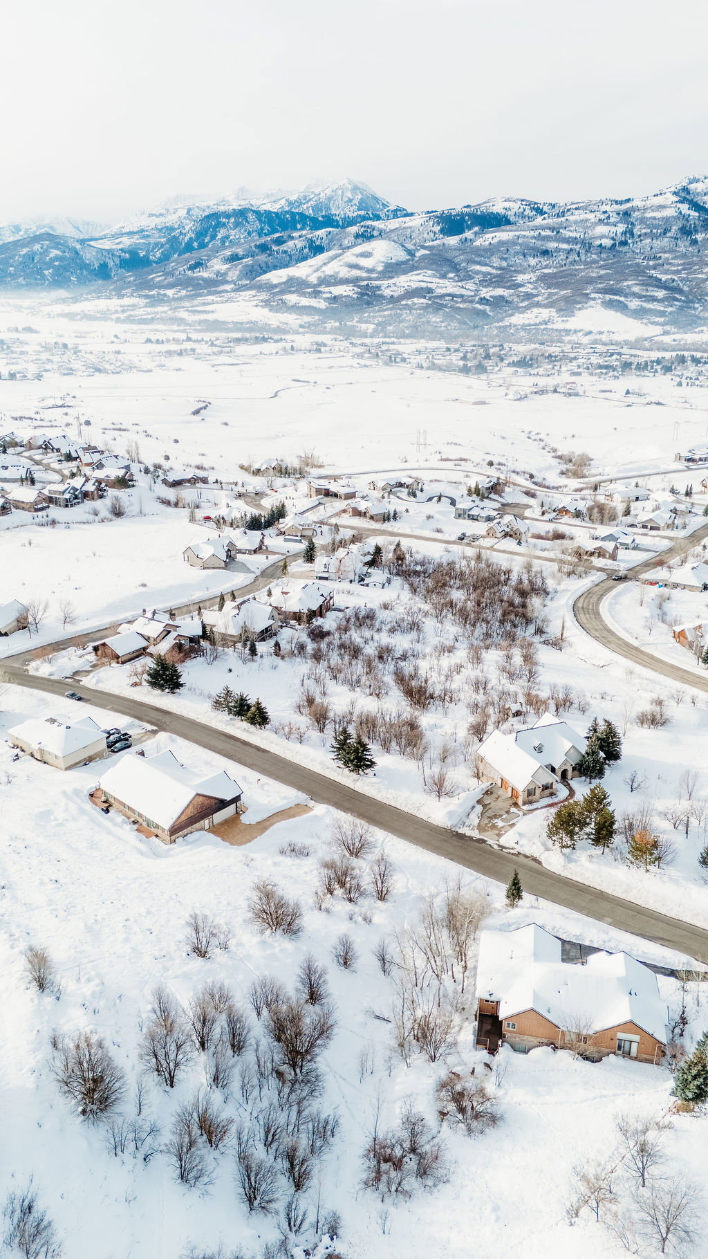 Snowy aerial view featuring a mountain view and a residential view