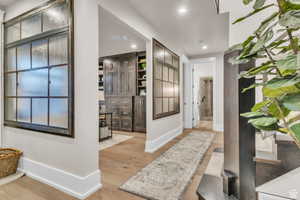 An architectural moment in itself, this light-filled hallway showcases custom windows and artisan-crafted paneling by a local artist, leading into a refined and private office space