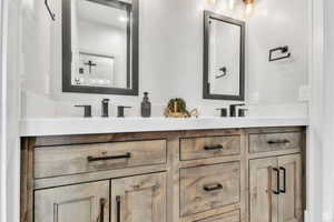 Private guest bathroom featuring dual vanities and custom metal-framed mirrors crafted by a local artist, adding a unique touch of character and craftsmanship to the space.