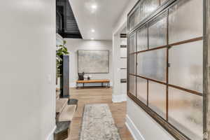 Bright hallway with custom windows and handcrafted paneled details by a local artist, leading into a private office space