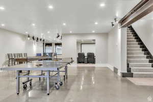 Expansive lower-level entertainment space featuring a dedicated game area with room for billiards, ping pong, and more. Designed for gathering and connection, this open layout flows seamlessly into a custom bar/kitchenette and leads directly to a private