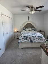 Bedroom with dark carpet, ceiling fan, a closet, and a textured ceiling