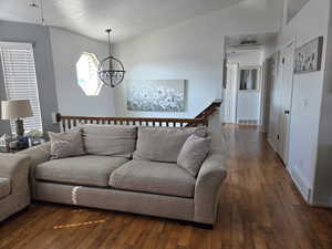 Living room with dark wood-style floors, hanging lights, and a textured ceiling