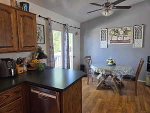 Kitchen featuring dishwasher, dark countertops, dark wood-style flooring, a peninsula, and ceiling fan