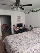 Carpeted bedroom with a textured ceiling and ceiling fan