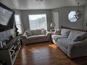 Living room featuring a textured ceiling, dark wood-type flooring, plenty of natural light, and a ceiling fan