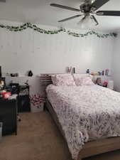 Bedroom featuring light colored carpet, an office area, and a ceiling fan