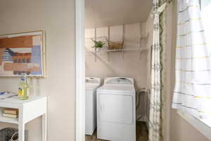 Laundry room with washer and clothes dryer, wood finished floors, and a textured wall