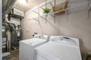 Laundry room featuring gas water heater, dark wood-style flooring, independent washer and dryer, and heating unit