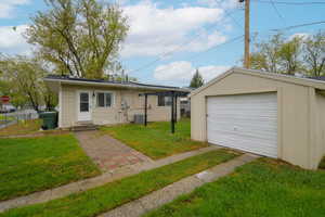 View of front of home with a front lawn, an outdoor structure, a garage, and entry steps