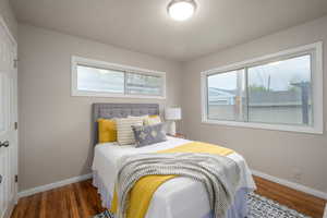 Bedroom with wood finished floors and multiple windows