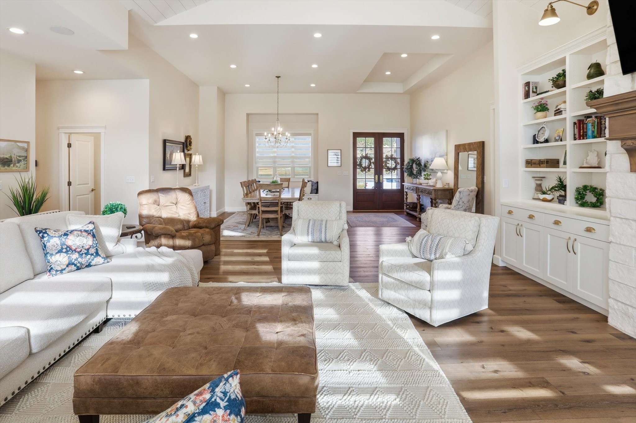 Living room featuring hanging lights, wood finished floors, built in shelves, and french doors