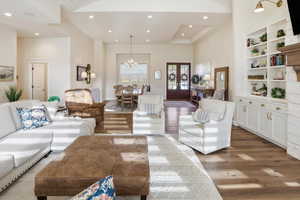 Living room featuring hanging lights, wood finished floors, built in shelves, and french doors