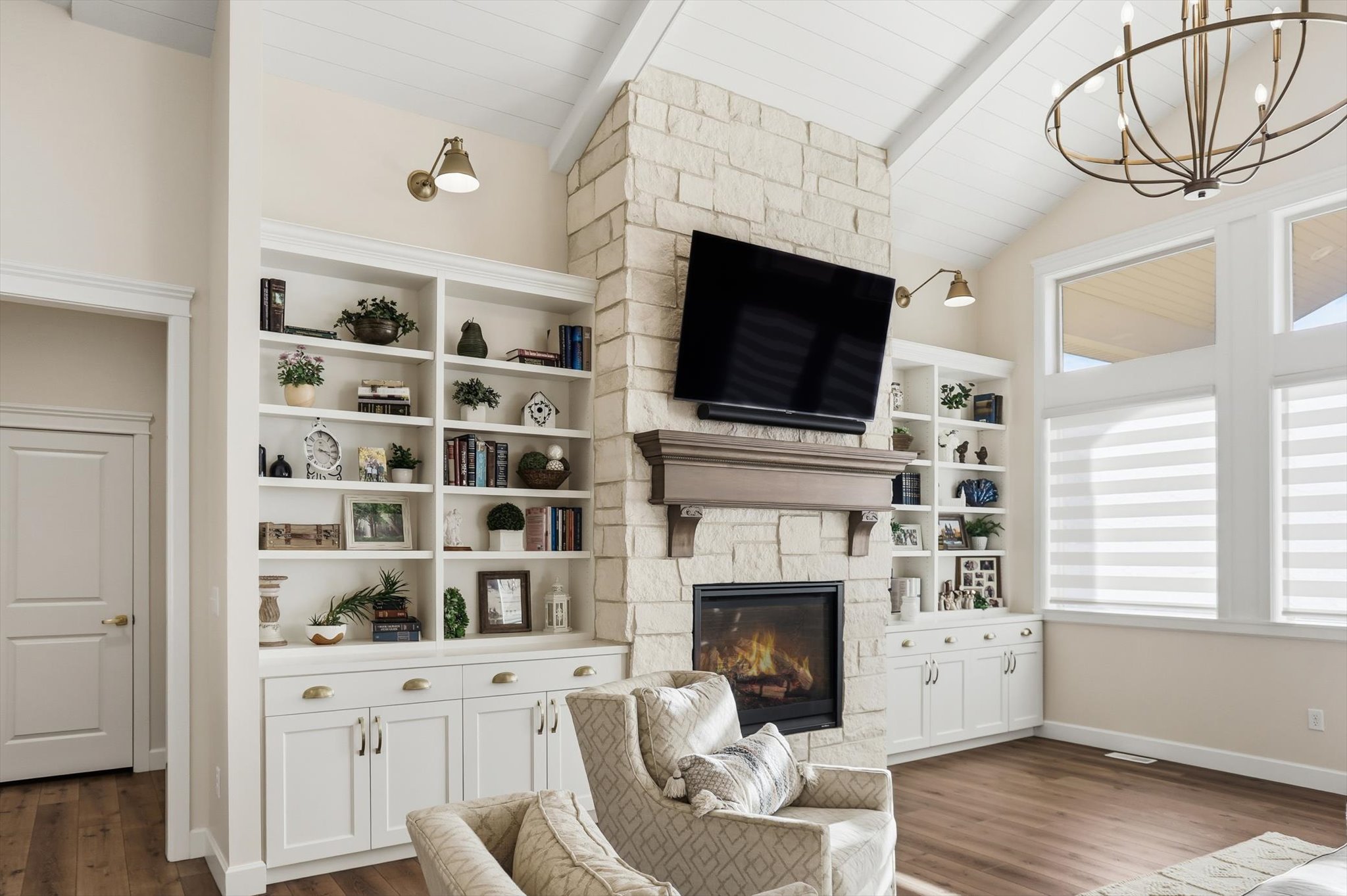 Living area with dark wood-style flooring, a stone fireplace, suspended lighting, lofted ceiling with beams, and wooden ceiling