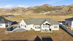 Back of property featuring a patio, stucco siding, roof with shingles, a mountain view, and a fenced backyard