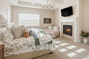 Carpeted bedroom with coffered ceiling, hanging lights, and a tiled fireplace