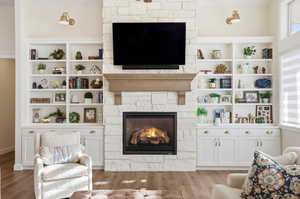 Living room featuring a fireplace, wood finished floors, built in shelves, and plenty of natural light