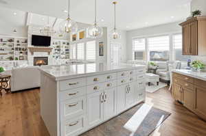 Kitchen featuring open floor plan, a fireplace, light wood-style floors, and a spacious island