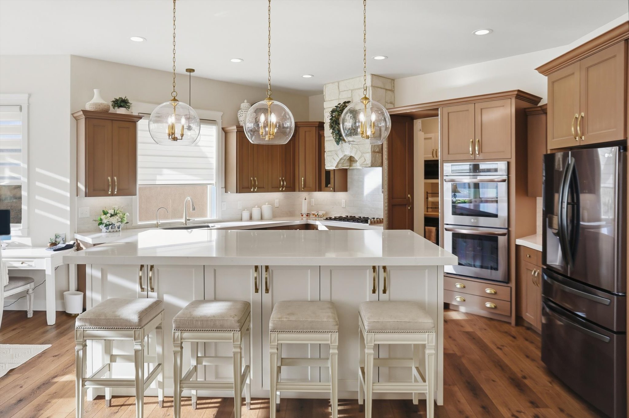 Kitchen featuring refrigerator with ice dispenser, a kitchen bar, a center island, stainless steel double oven, and pendant lighting
