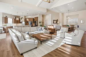 Living area featuring a chandelier, light wood-style floors, and a high wood beamed ceiling