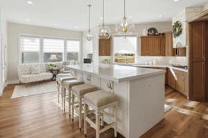 Kitchen featuring wood finish cabinets, a kitchen bar, a center island, light wood finished floors, and light stone counters
