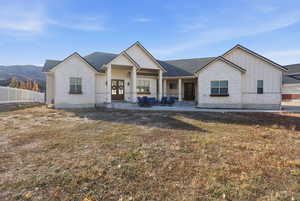View of front of house with board and batten siding, stone siding, covered porch, french doors, and a mountain view