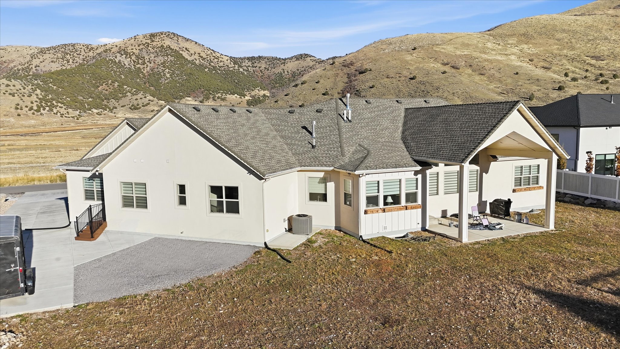 Back of house with a patio, a shingled roof, a mountain view, and stucco siding